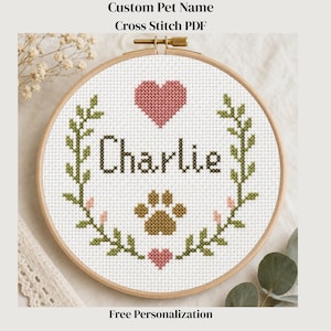 May include: A cross-stitch design with the name "Charlie" in brown thread, framed by green leaves, pink hearts, and a paw print. The text "Custom Pet Name Cross Stitch PDF" and "Free Personalization" are also included in the design.