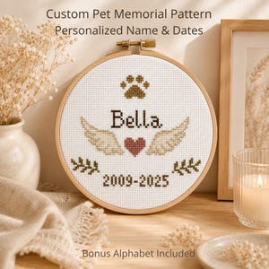 May include: A custom pet memorial cross-stitch pattern in a wooden hoop. The design includes a paw print, the name "Bella", wings, a heart, dates, and text that reads "Custom Pet Memorial Pattern Personalized Name & Dates".