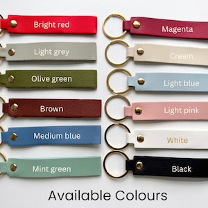 May include: A collection of leather keychains in various colors, including bright red, light grey, olive green, brown, medium blue, mint green, magenta, cream, light blue, light pink, white, and black. Each keychain has a gold-colored ring and the text "Available Colours".