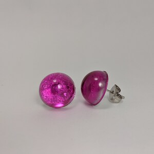 May include: A pair of pink glass stud earrings with silver posts.