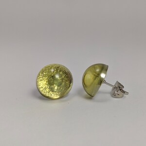 May include: A pair of green glass stud earrings with silver posts.