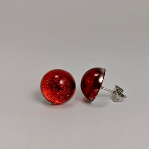 May include: A pair of red glass stud earrings with silver posts.