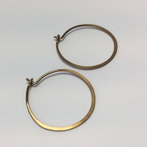 May include: A pair of gold hoop earrings. The earrings are simple and elegant, with a smooth, polished finish.