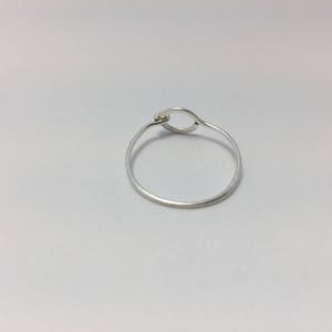 以下が含まれることがあります： 円形のデザインが施されたシルバーリング。リングは細いワイヤーで作られており、シンプルでミニマルなスタイルです。