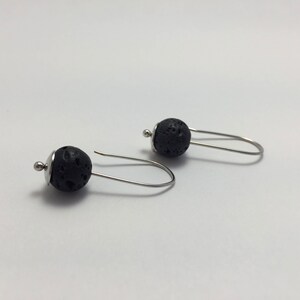 May include: A pair of silver earrings with black lava rock beads. The earrings are simple and elegant, and would make a great gift for any occasion.
