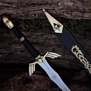 May include: A decorative sword with a silver blade and gold accents. The hilt is black with gold detailing, and the guard features a wing-like design. The scabbard is black with gold Celtic-style patterns and a gold tip.
