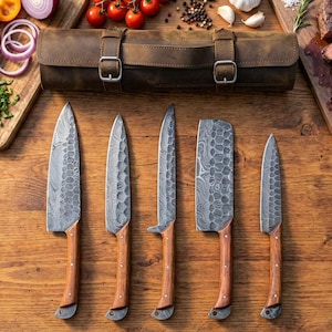May include: A set of five stainless steel kitchen knives with wooden handles, arranged on a wooden surface. The blades have a unique patterned design. A brown leather knife roll is in the background.