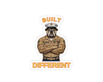 May include: A sticker featuring a bulldog in a military uniform with the words "BUILT" above and "DIFFERENT" below. The bulldog is wearing a tan uniform, a white hat, and has its arms crossed.