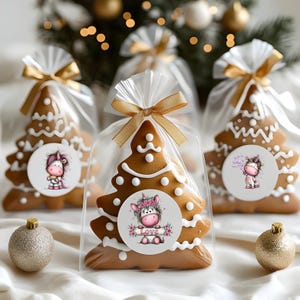 Puede incluir: Galletas de jengibre con forma de &aacute;rbol de Navidad decoradas con glaseado blanco y empaquetadas en bolsas de celof&aacute;n transparente atadas con cinta dorada. Cada galleta tiene una pegatina redonda con un dise&ntilde;o de unicornio de dibujos animados.