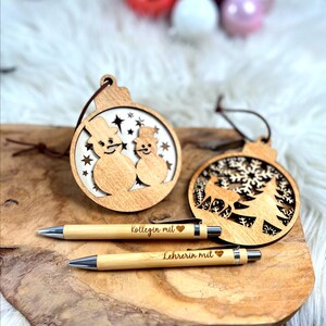Wichtelgeschenk Kollegin, Kugelschreiber als Geschenk mit Gravur, Personalisierte Kulis, Mitarbeiter Geschenke Weihnachten - zwei Kugelschreiber mit der Gravur "Kollegin mit Herz" und "Lehrerin mit Herz" und zwei Weihnachtsanhänger aus Holz mit einem Schneemännermotiv und einem Hirsch mit Tannenbaum Motiv.