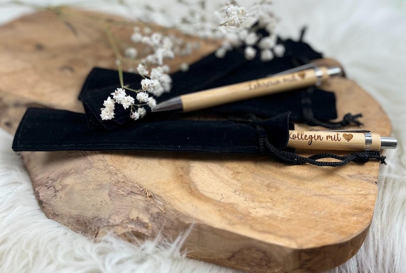 Wichtelgeschenk Kollegin, Kugelschreiber als Geschenk mit Gravur, Personalisierte Kulis, Mitarbeiter Geschenke Weihnachten - zwei Kugelschreiber mit der Gravur "Kollegin mit Herz" und "Lehrerin mit Herz" mit schwarzen Samtsäckchen als Verpackung.