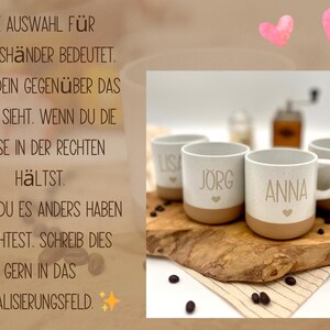 May include: Four personalized coffee mugs with names "Lisa", "Jorg", "Anna", and "Mia" are displayed on a wooden board. Each mug has a white speckled upper half and a tan base, with a small heart below the name. Coffee beans and a grinder are also visible.