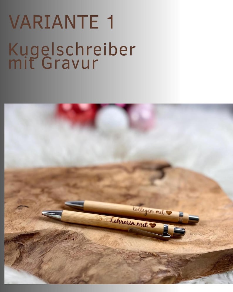 May include: Two wooden pens with silver accents and engraved text. One pen reads "Lehrerin mit" and the other reads "Kollegin mit", both with a heart symbol. The pens are displayed on a wooden surface.