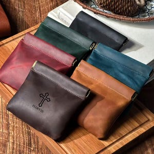 May include: A collection of six small leather pouches in various colors including dark brown, tan, red, green, blue, and black. The dark brown pouch features a stamped cross symbol and the text HARVIE. Each pouch has a metal frame closure.