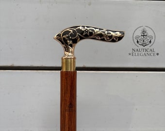 May include: A wooden walking cane with a brass handle and accents. The handle is black with a floral design. The cane is a dark brown color and has a brass collar. The logo "NAUTICAL ELEGANCE" is visible.