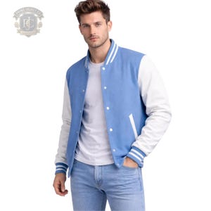 Könnte beinhalten: Eine hellblaue Collegejacke mit weißen Ärmeln, einer weißen Druckknopfleiste vorne und weiß gestreiften Rippbündchen an Kragen, Ärmeln und Saum. Die Jacke verfügt über zwei Seitentaschen und wird über einem schlichten weißen T-Shirt getragen.