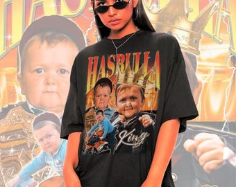 May include: Black t-shirt with a graphic of a person wearing a crown and the word "HASBULLA" in orange. The shirt features multiple images of the person. The background has a gold crown and lightning bolts.