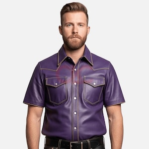 May include: A short-sleeved, purple leather shirt with a classic collar and two chest pockets. The shirt features tan stitching and white buttons. The model is wearing a black belt.