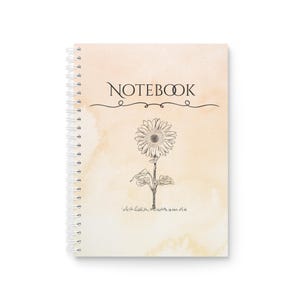 Pode incluir: Caderno espiral com fundo em estilo aquarela em tons de pêssego e creme. A palavra "NOTEBOOK" está escrita acima de uma ilustração detalhada de girassol em preto e branco. O caderno tem um design simples e elegante.