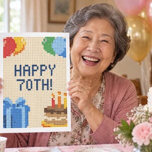 Puede incluir: Un proyecto de manualidades de pintura de diamantes rectangular con fondo beige, un diseño pixelado de globos coloridos, una caja de regalo azul, un pastel de cumpleaños con velas encendidas y el texto azul oscuro HAPPY 70TH!