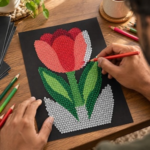 May include: A black sheet of paper featuring a dot-to-dot style illustration of a tulip in a pot. The tulip petals are filled with red and pink dots, while the leaves are green dots. The pot is outlined with white dots, and colored pencils are used.
