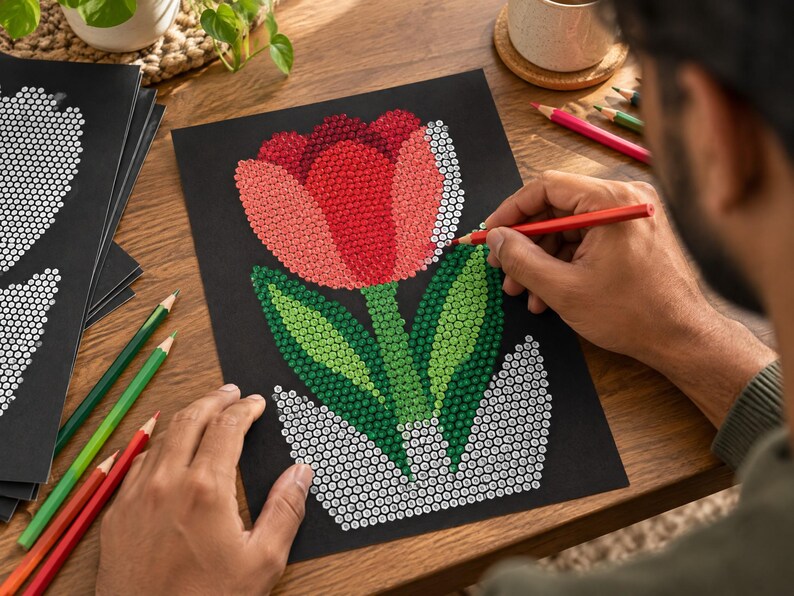 May include: A black sheet of paper featuring a dot-to-dot style illustration of a tulip in a pot. The tulip petals are filled with red and pink dots, while the leaves are green dots. The pot is outlined with white dots, and colored pencils are used.