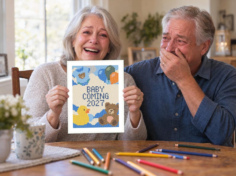 May include: A rectangular white card featuring a pixelated cross-stitch style design with the text BABY COMING 2027. The illustration includes a yellow rubber duck, a brown teddy bear, and blue, green, and orange balloons against a white background.