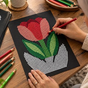 Pu&ograve; includere: Un foglio di carta nero con un'illustrazione in stile puntinista di un tulipano in un vaso. I petali del fiore sono colorati in tonalit&agrave; di rosso e rosa, le foglie sono verdi e il vaso &egrave; bianco. Il disegno &egrave; composto da piccoli punti distinti.