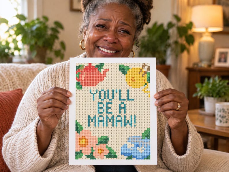 Op de afbeelding: Een rechthoekig diamond painting knutselproject met een lichtbeige achtergrond en een rasterpatroon. De tekst "YOU'LL BE A MAMAW!" is gedrukt in blauwgroen. Decoratieve elementen zijn onder meer een rode theepot, een gele citroen en roze en blauwe bloemen.