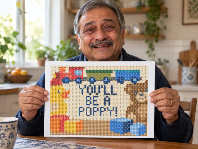 Puede incluir: Una impresi&oacute;n rectangular con un dise&ntilde;o pixelado y el texto YOU'LL BE A POPPY! en azul oscuro. La imagen incluye un tren rojo y azul, un pato de goma amarillo, un oso de peluche marr&oacute;n y bloques azules sobre un fondo de color beige.
