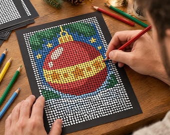 May include: A dot-to-dot coloring sheet on black paper featuring a red and yellow Christmas ornament design. The artwork is composed of a grid of white circles, some of which are filled in with red, yellow, green, and blue colored pencil.