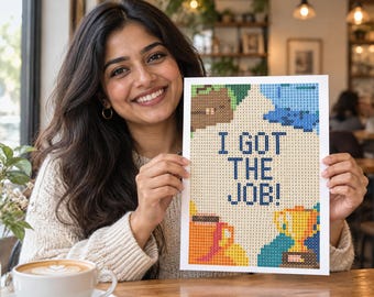 Könnte beinhalten: Ein rechteckiges Diamond-Painting-Bastelprojekt mit einem Rastermuster und dem Text I GOT THE JOB! in Dunkelblau. Das Design enthält bunte, verpixelte Illustrationen einer braunen Aktentasche, eines goldenen Pokals und einer Kaffeetasse auf hellem Grund.