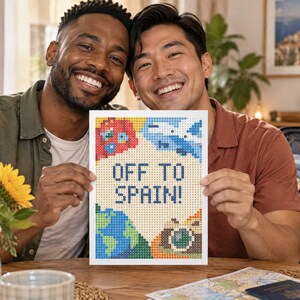 May include: A rectangular diamond painting art piece featuring the text OFF TO SPAIN! in dark blue block letters. The design includes colorful pixelated illustrations of a red sun, a blue airplane, a green and blue globe, and a brown camera.