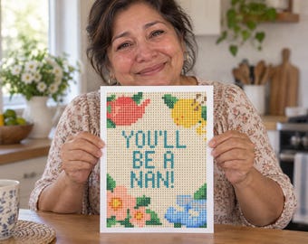Könnte beinhalten: Ein rechteckiges Diamond-Painting-Bastelprojekt mit einem Gittermuster und dem blauen Schriftzug "YOU'LL BE A NAN!". Das Design zeigt eine rote Teekanne, eine gelbe Zitrone, rosa Blumen und blaue Blumen, die aus kleinen Quadraten bestehen.