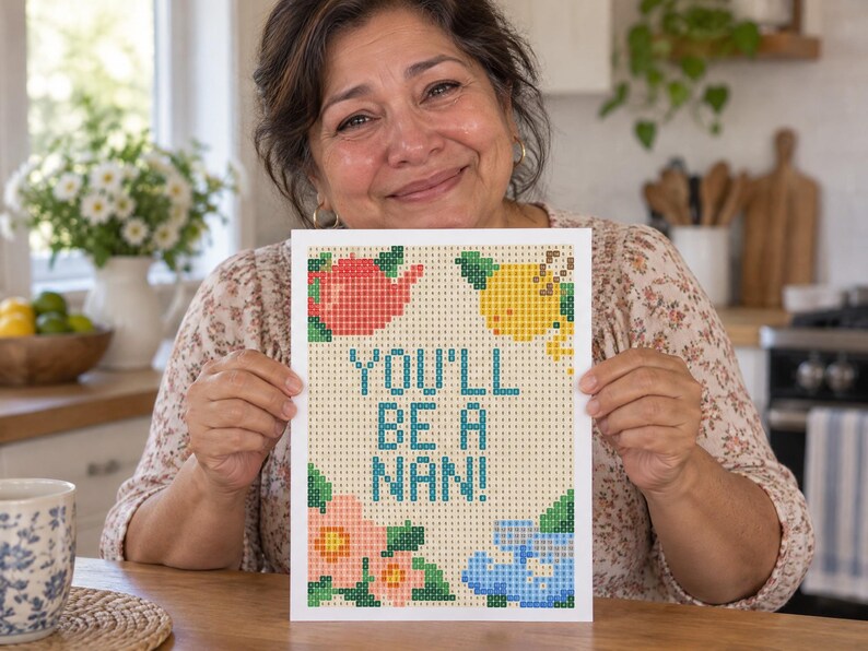 May include: A rectangular diamond painting craft project featuring a grid pattern with the text "YOU'LL BE A NAN!" in blue. The design includes a red teapot, a yellow lemon, pink flowers, and blue flowers, all composed of small square tiles.