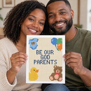 May include: A rectangular white card featuring a cross-stitch style design with the text BE OUR GOD PARENTS in dark blue. The design includes a blue baby onesie, a cluster of blue, green, and orange balloons, a yellow rubber duck, and a brown teddy bear.