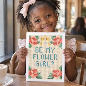 K&ouml;nnte beinhalten: Eine rechteckige Karte mit einem pixeligen Kreuzstich-Design und dem Text BE MY FLOWER GIRL? in blauen Buchstaben. Das Motiv zeigt rosa und pfirsichfarbene Rosen mit gr&uuml;nen Bl&auml;ttern in den Ecken auf einem hellbeigen Rasterhintergrund.