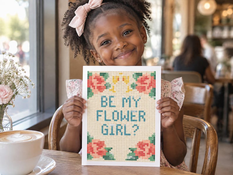 K&ouml;nnte beinhalten: Eine rechteckige Karte mit einem pixeligen Kreuzstich-Design und dem Text BE MY FLOWER GIRL? in blauen Buchstaben. Das Motiv zeigt rosa und pfirsichfarbene Rosen mit gr&uuml;nen Bl&auml;ttern in den Ecken auf einem hellbeigen Rasterhintergrund.