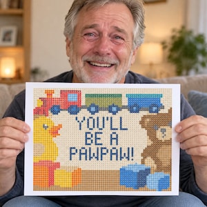 Puede incluir: Una impresión rectangular con un diseño pixelado de un tren de juguete, un pato de goma amarillo y un oso de peluche marrón. El texto en el centro dice "YOU'LL BE A PAWPAW!". El diseño utiliza un patrón de cuadrícula con varios colores como rojo, azul y naranja.