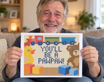May include: A rectangular print featuring a pixelated design of a toy train, a yellow rubber duck, and a brown teddy bear. The text in the centre reads, "YOU'LL BE A PAWPAW!" The design uses a grid-like pattern with various colours including red, blue, green, and orange.