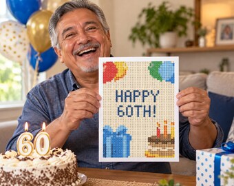 May include: A rectangular print featuring a pixelated design with the text HAPPY 60TH! in blue. The artwork includes colorful balloons in red, yellow, green, and blue, a blue gift box, and a birthday cake with three lit candles on a cream background.
