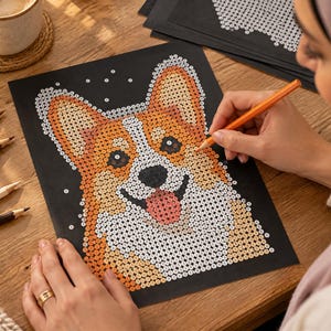 May include: A paint-by-number activity sheet on black paper featuring a Corgi dog illustration. The design is composed of small numbered circles in shades of orange, white, black, and pink, waiting to be filled with color to complete the portrait.