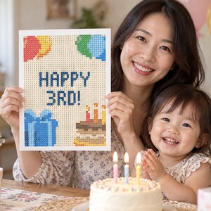 Puede incluir: Un proyecto de manualidades de diamond painting rectangular con un dise&ntilde;o pixelado que incluye el texto HAPPY 3RD! en azul, acompa&ntilde;ado de globos de colores, una caja de regalo azul y un pastel de cumplea&ntilde;os con tres velas encendidas sobre fondo blanco.