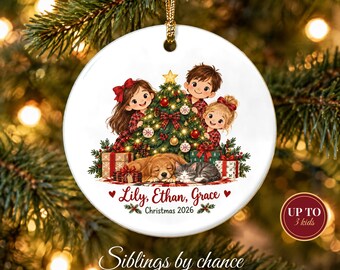 May include: A round white ceramic Christmas ornament featuring an illustration of three children, a dog, and a cat around a decorated tree. The text reads Lily, Ethan, Grace and Christmas 2026. It hangs from a gold cord.