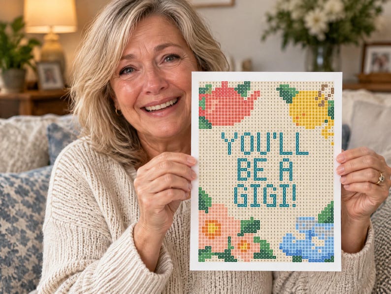 May include: A rectangular diamond painting canvas featuring a grid pattern with the text YOU'LL BE A GIGI! in blue. The design includes a pink teapot, a yellow lemon, a pink flower, and a blue baby onesie, all rendered in a pixelated style.