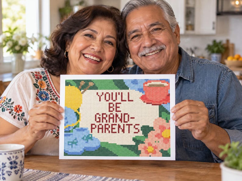 May include: A rectangular sign featuring a pixelated cross-stitch design with the text YOU'LL BE GRANDPARENTS in dark red letters. The artwork includes a yellow ball of yarn, blue baby booties, a red coffee cup, and pink flowers on a green background.