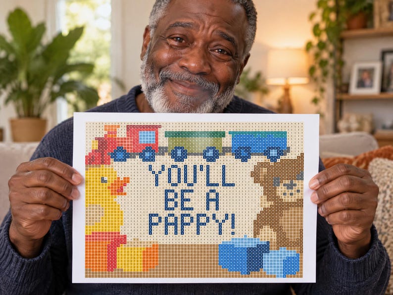 K&ouml;nnte beinhalten: Ein rechteckiger Druck mit einem verpixelten Design und dem Text YOU'LL BE A PAPPY! in Dunkelblau. Das Bild zeigt einen rot-blauen Zug, eine gelbe Quietscheente, einen braunen Teddyb&auml;ren und blaue Bl&ouml;cke, alles in einem gitterartigen Muster.