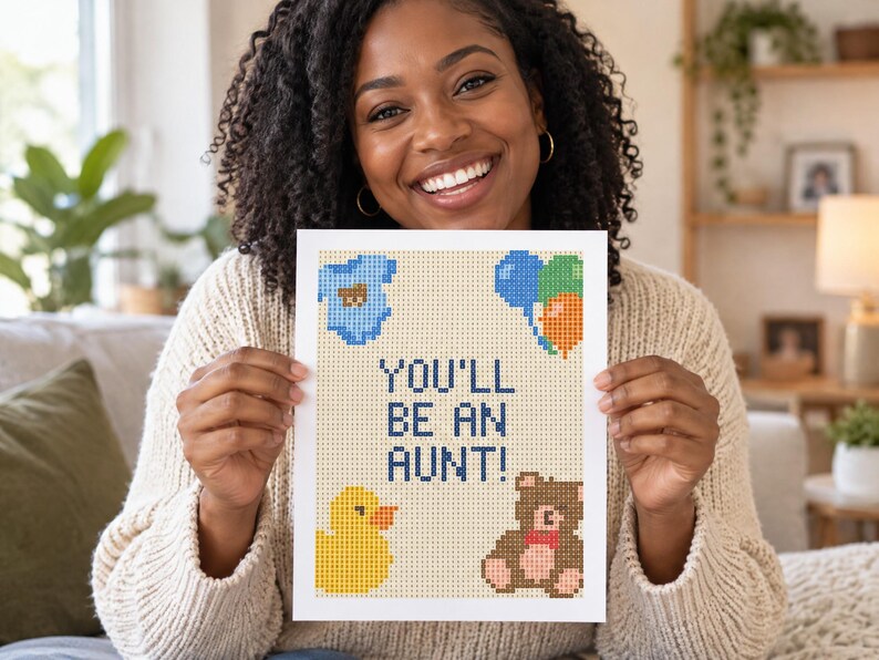 May include: A rectangular white card featuring a pixel-art style design with the text YOU'LL BE AN AUNT! in dark blue. The card includes a light blue baby onesie, a cluster of blue, green, and orange balloons, a yellow rubber duck, and a brown teddy bear.