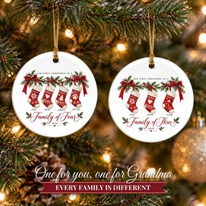 May include: Two round white ceramic ornaments with gold hanging strings. The left ornament features four red stockings with names Dad, Mom, Emma, Buddy and text Our First Christmas as a Family of Four 2026. The right shows three stockings with names Dad, Mom, Liam and text Our First Christmas as a Family of Three 2026.