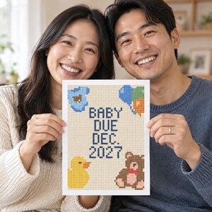 May include: A rectangular white sign featuring a pixelated cross-stitch design with the text "BABY DUE DEC. 2027" in dark blue. The design includes a blue baby onesie, colourful balloons, a yellow rubber duck, and a brown teddy bear with a red bow.